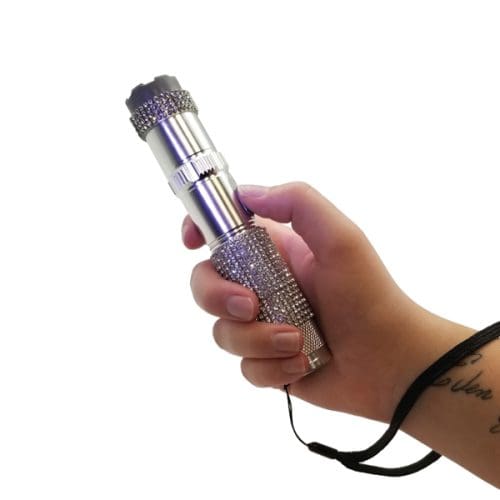 Hand holding a silver rhinestone flashlight with wrist strap.