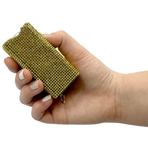 Hand holding a golden rhinestone-covered rectangular object against white background.