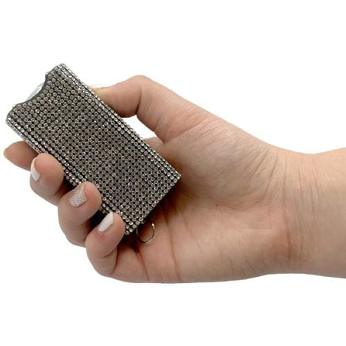 Hand holding a rhinestone-covered stun gun for self-defense, showcasing an elegant design.