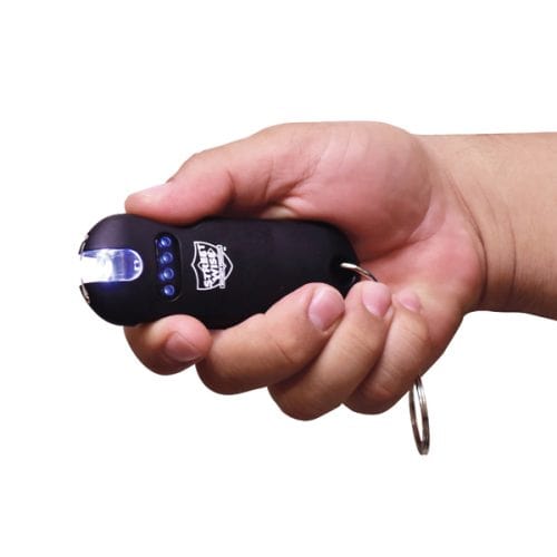 Hand holding a black keychain flashlight with blue indicator lights and a glowing bulb.