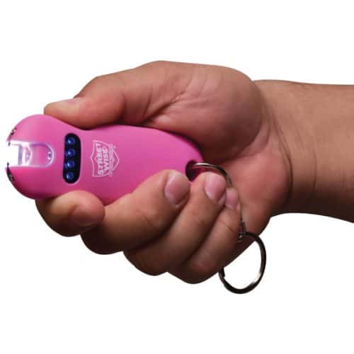 Person holding a pink compact stun gun with a keychain for self-defense.