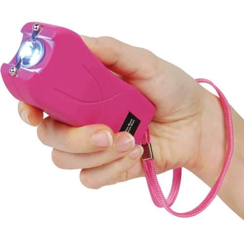 Person holding a pink stun gun with light activated, attached to a wrist strap.